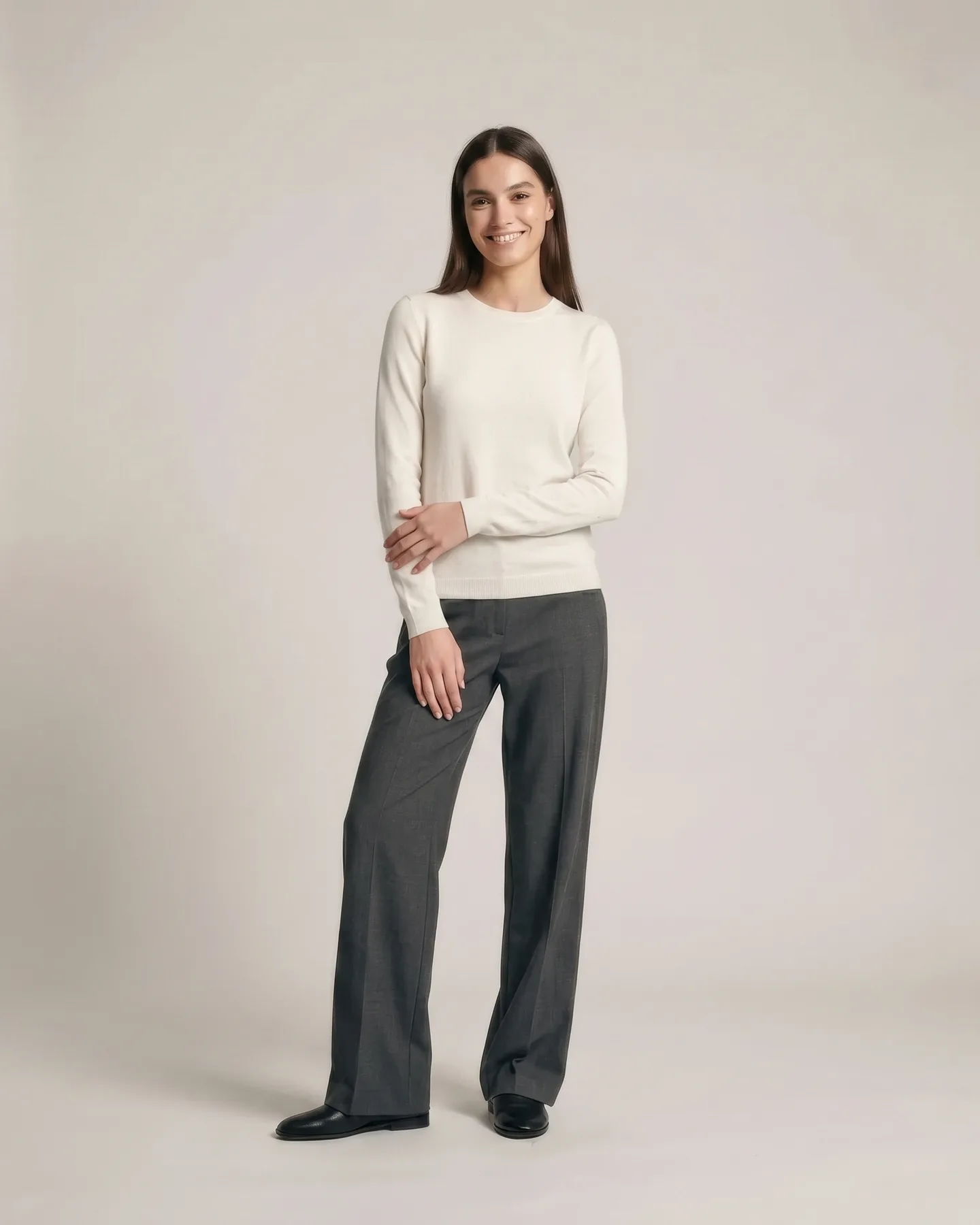 The same look, relaxed and smiling, one hand resting on the opposite forearm