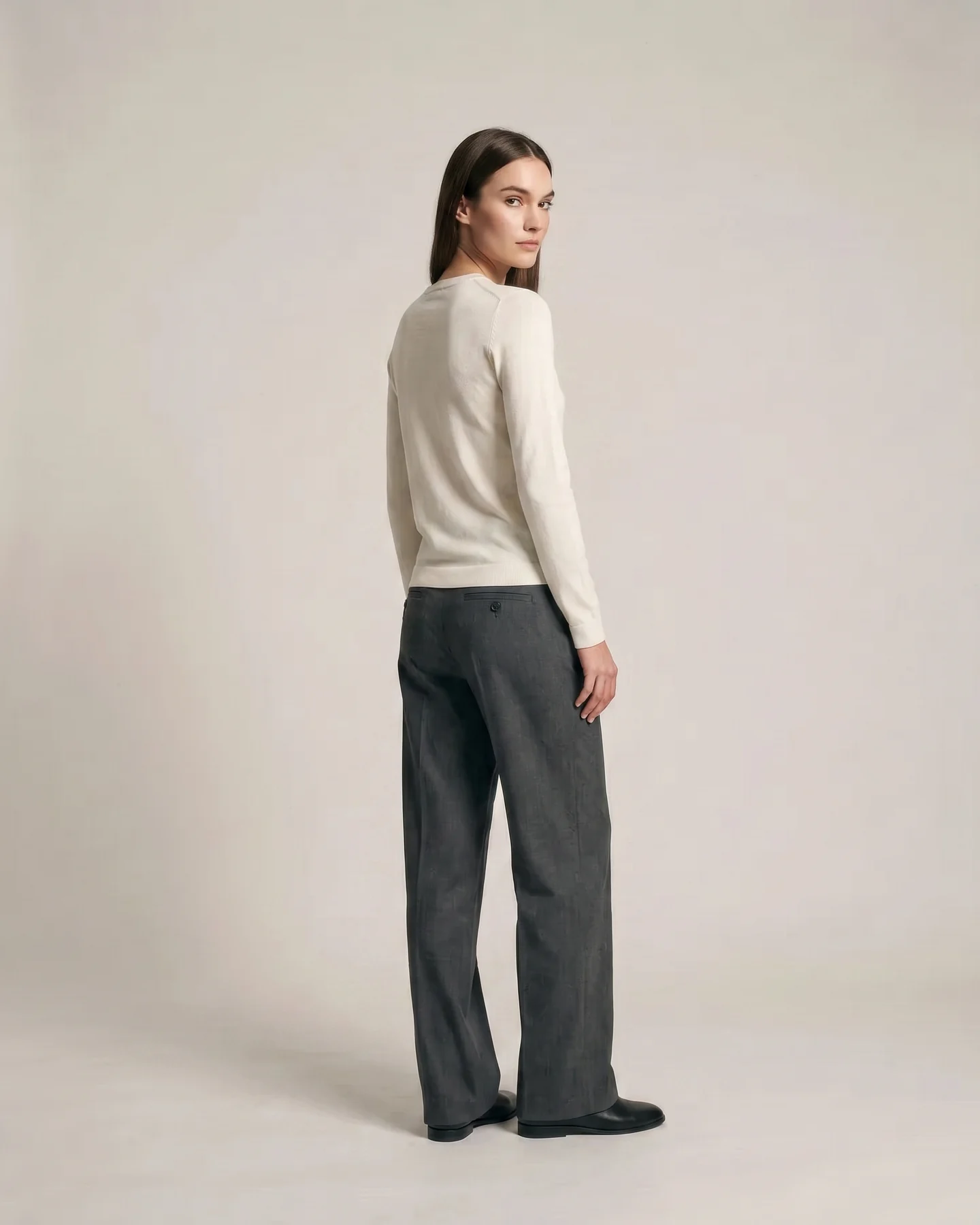 Turned three-quarters away, the shoulder line carrying the knit